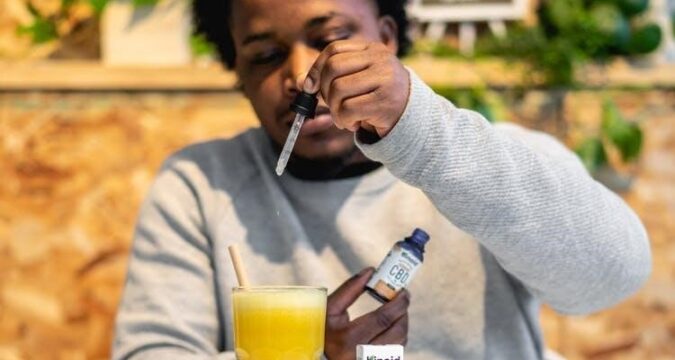A young man uses CBD oil in his drink